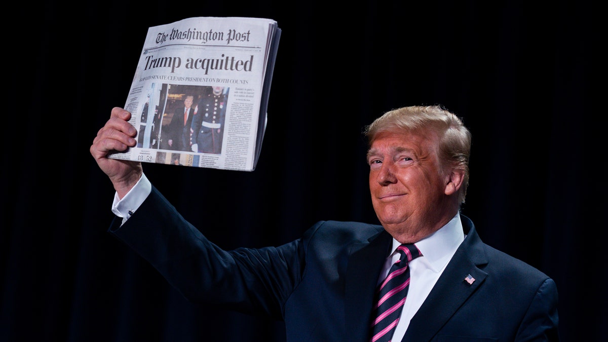 Then-President Trump holds up a newspaper with the headline that reads "Trump acquitted" during the 68th annual National Prayer Breakfast at the Washington Hilton on Feb. 6, 2020, in Washington, D.C.