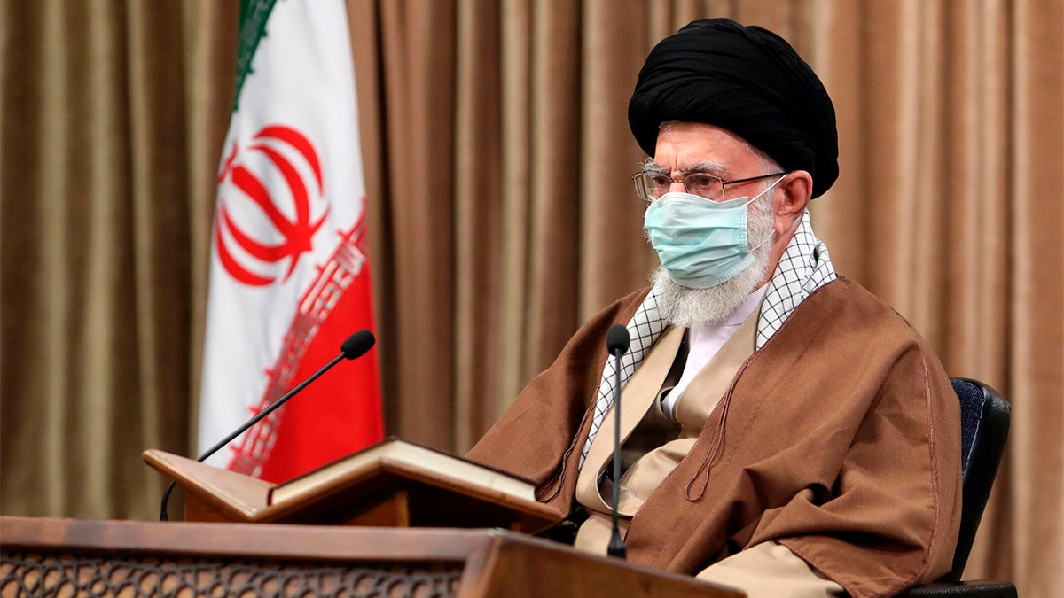 Ayatollah Ali Khamenei speaks while wearing mask in front of an Iranian flag